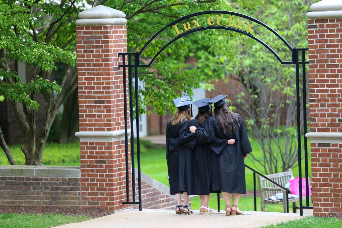 F&M graduates standing beneath the Lux et Lex arch